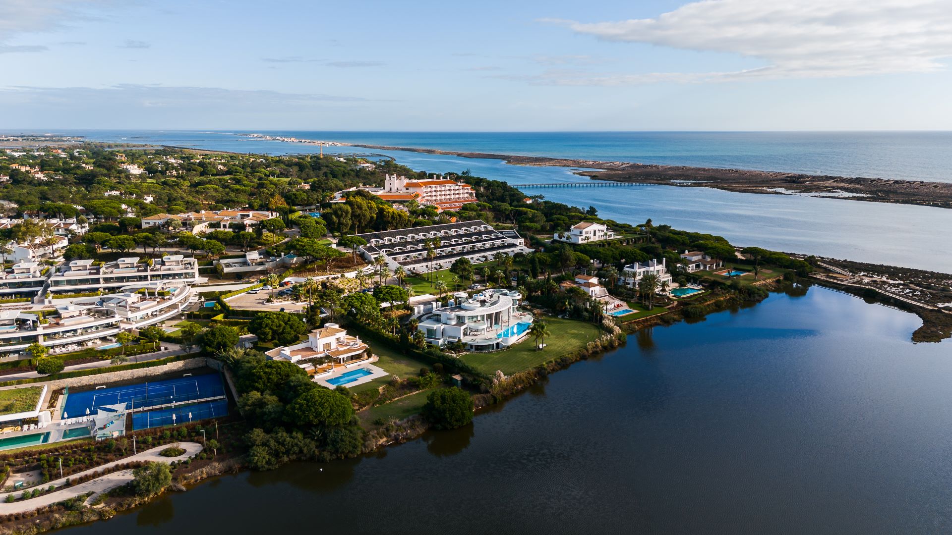 Aerial view of an exclusive lagoon side residential enclave with luxury villas and resort amenities along Portugal’s Algarve coastline.
