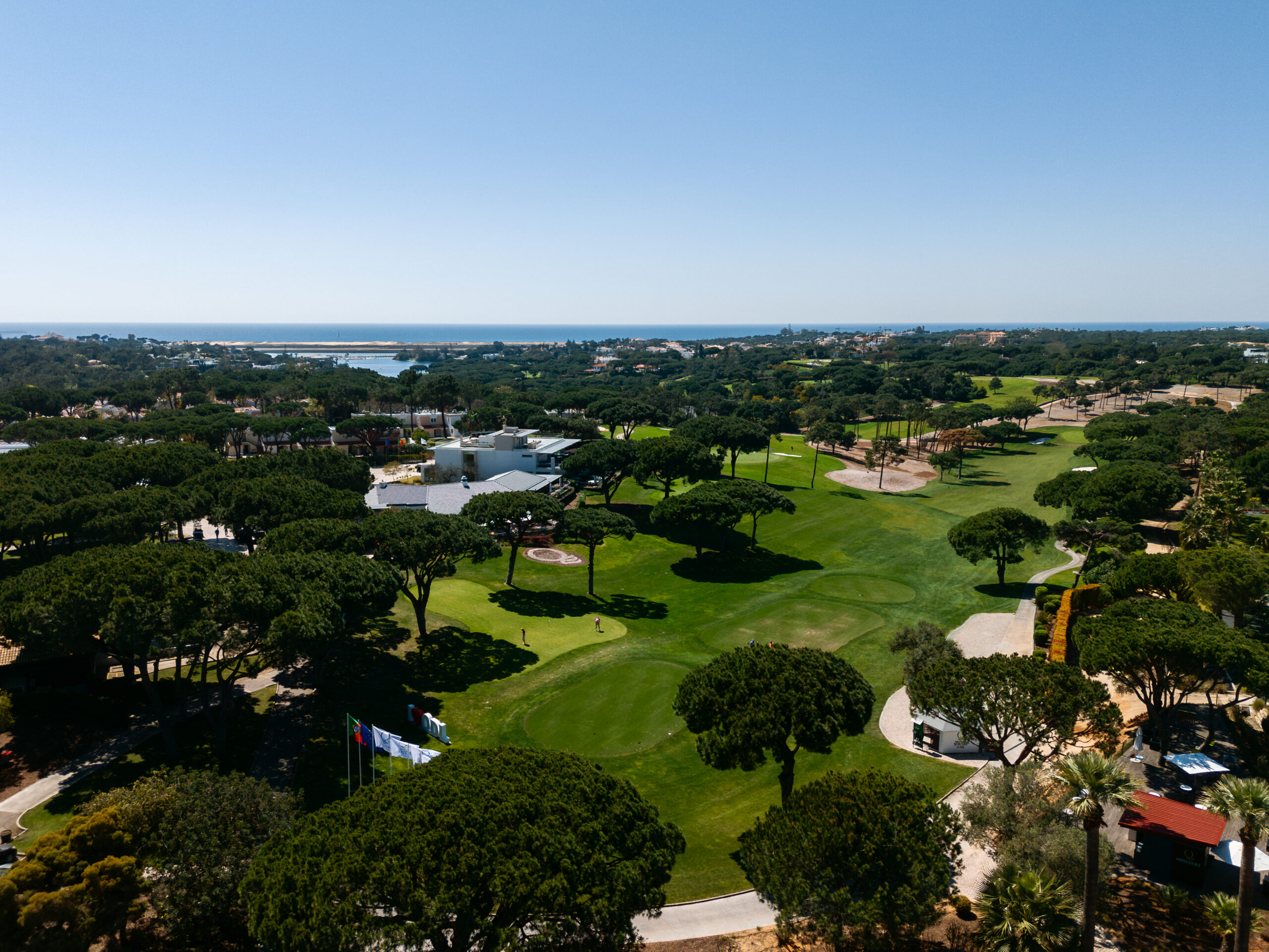 Aerial view of Quinta do Lago golf course with pine trees, luxury homes and the Atlantic Ocean in the distance
